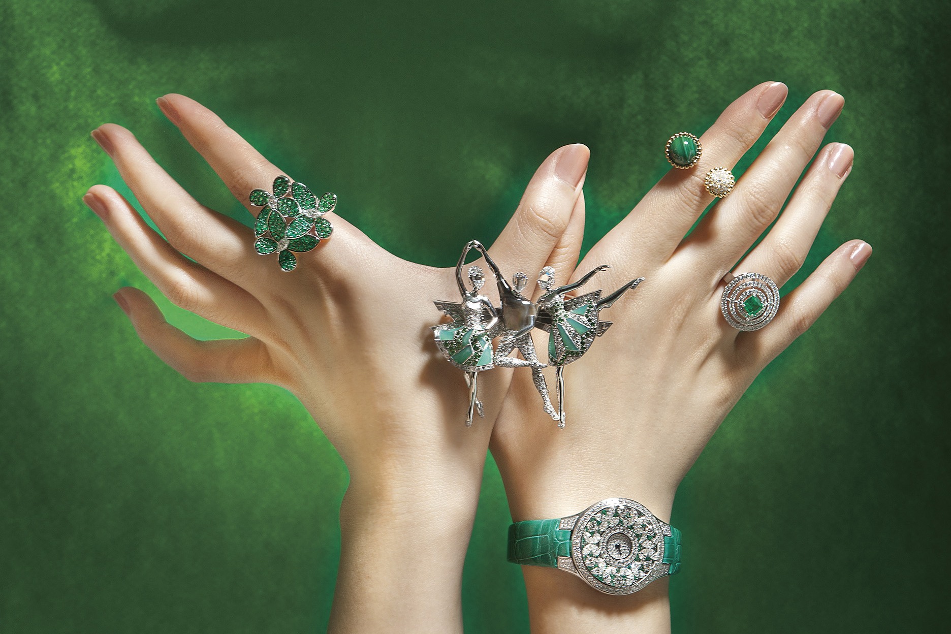 （左手） Pas de Trois Chrysoprase 胸針 by Van Cleef & Arpels 、繾綣蝴蝶系列多形切割祖母綠和鑽石戒指 by Graff 。（右手） Pas de Trois Chrysoprase 胸針 by Van Cleef & Arpels 。 Bullseye 系列祖母綠形切割祖母綠和圓形鑽石戒指、蝴蝶造型腕錶配祖母綠和鑽石 by Graff 。